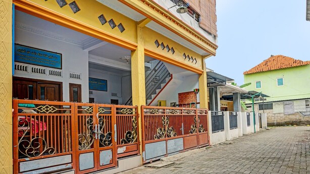 A building with a yellow facade, a staircase, and a gated entrance.