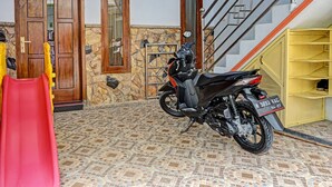 A motorcycle parked near a staircase, a red slide, and a stone wall.