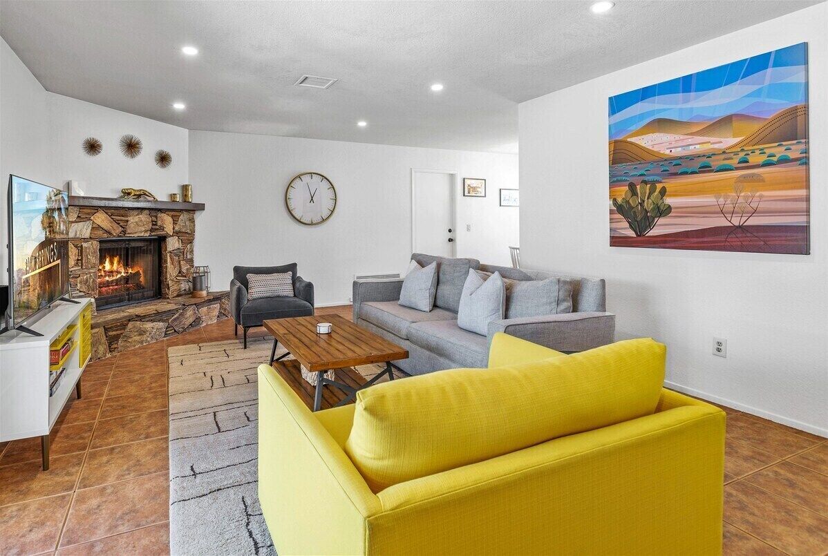 A living room with a stone fireplace, a sofa, a coffee table, and a painting on the wall.