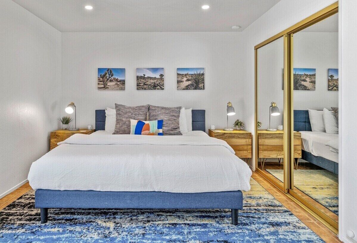 Un dormitorio con una cama grande, mesitas de noche, un escritorio y un espejo.