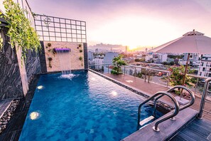 A rooftop pool with a waterfall feature, surrounded by a cityscape view. - Laurel Danang Apartment (Da Nang)