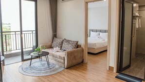 Une chambre d’hôtel moderne dotée d’un balcon, d’un canapé, d’une petite table et d’un lit.