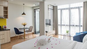 Une chambre d’hôtel comprenant un lit, un bureau, une chaise, une petite table avec une plante et un téléviseur.