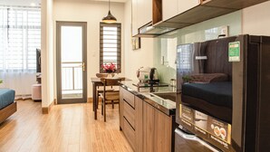 Une cuisine de taille réduite, dotée de meubles de rangement en bois, d’un plan de travail et d’un réfrigérateur encastré.