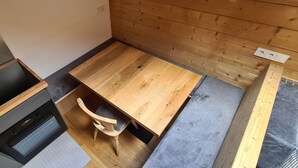 Una cucina compatta con forno a incasso, un tavolo di legno e una sedia.
