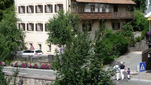 Un edificio a più piani con un balcone, un segnale di attraversamento pedonale e un divieto di parcheggio.