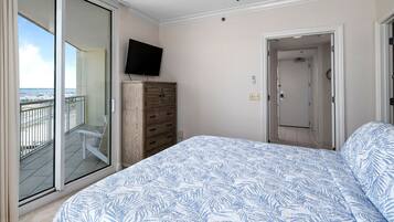 Ein Schlafzimmer mit einem Bett, einem Fernseher, einem Kleiderschrank und einer Schiebetür zum Balkon.
