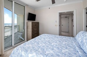 Un dormitorio con cama, televisión, armario y puerta corrediza de vidrio a un balcón.