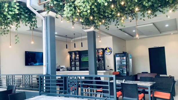 Een restaurant met terras, een bar en hangende begroeiing.