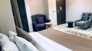 Een hotelkamer met een bed, een bank, een stoel en een kleine tafel.