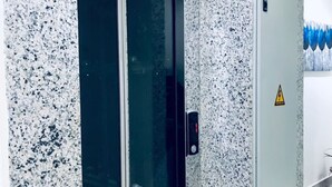 Een moderne lift met glazen deur, geplaatst in een gebouw met wanden van gespikkelde graniet.