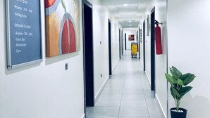 Een lange, goed verlichte hal met een bord waarop kamer nummers en faciliteiten staan vermeld.