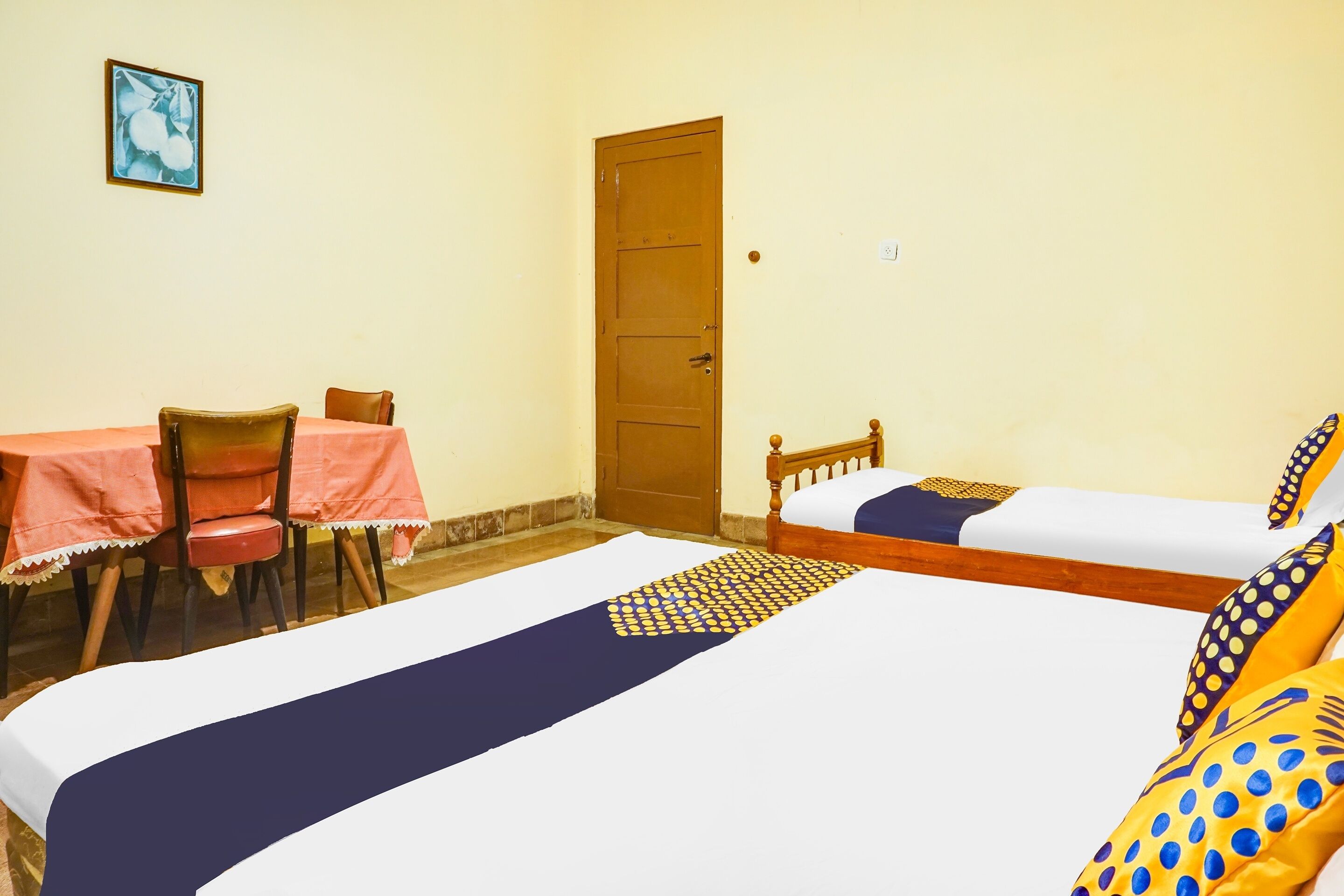 A room with two beds, a table with chairs, and a door.