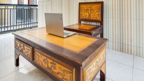 Et træskrivebord med detaljerede udskæringer, en bærbar computer ovenpå og en stol med lignende udskæringer.