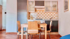 A compact kitchen with a dining table and chairs, a stove, and cabinets.