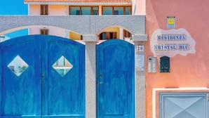 A building with a sign reading "RESIDENZA CRISTAL BLU" and a blue gate.