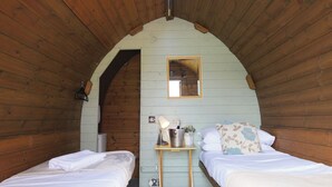 A cozy attic bedroom with two beds, a small table with a lamp, and a mirror on the wall. - Ocean View 1 - 1 Bed Pod - Llanrhidian (Swansea)