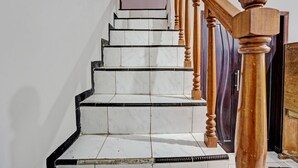 Una escalera con baldosas blancas y negras, barandillas de madera y una puerta al final.