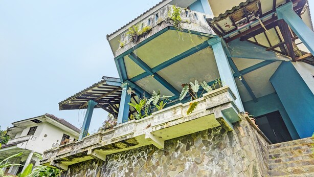 Un edificio de varios pisos con balcón, paredes de piedra y una combinación de colores azul y blanco.