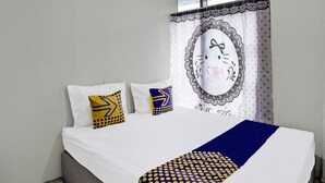 Una cama con ropa de cama blanca, dos almohadas con diseños amarillos y azules, y una manta azul y amarilla.