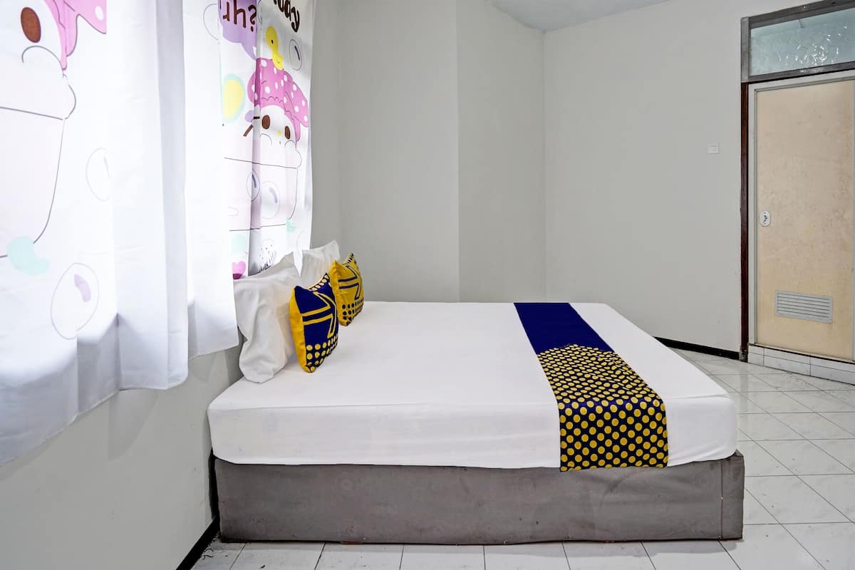 A bedroom with a bed, pillows, and a curtain with a cartoon character.
