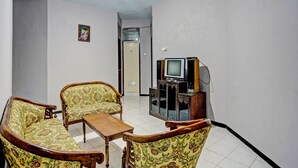 Una sala de estar con un sofá, una mesa de centro de madera y un televisor sobre un mueble.