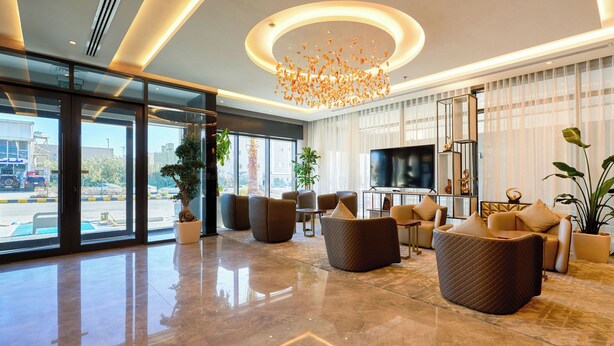 Un vestíbulo moderno con un televisor grande, asientos cómodos y ventanas amplias que ofrecen vistas al exterior.