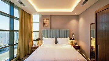 A hotel room with a large bed, a nightstand, a bedside lamp, a telephone, and a window with curtains.