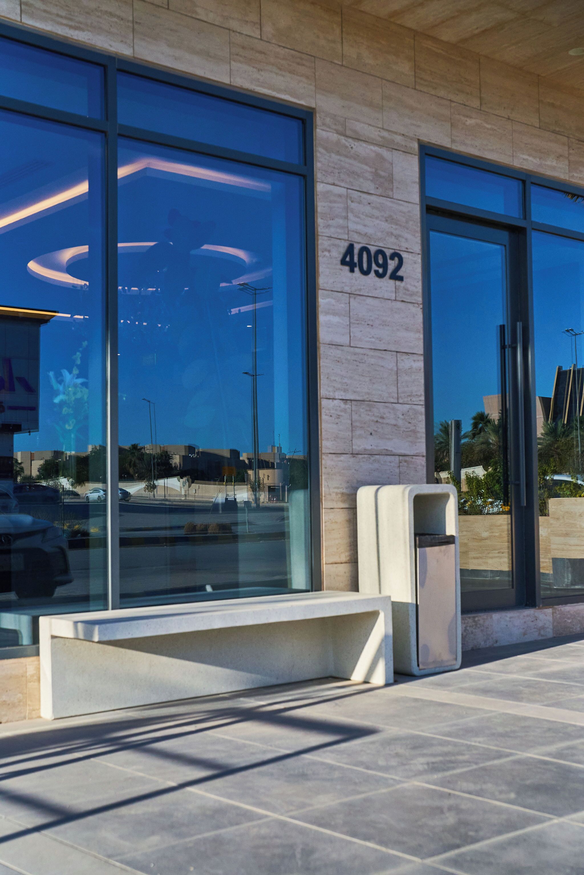 A modern building with large glass windows, a visible number '4092', and a bench outside.