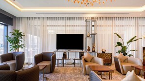 Una sala de estar moderna con un televisor de pantalla plana, asientos cómodos y plantas decorativas.