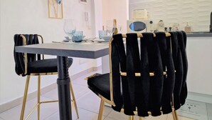 A dining area with a table, chairs, and a kitchen in the background. - The Golden House (Siracusa)