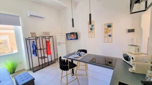 A modern kitchen with a dining area, a small refrigerator, a TV, and a toaster. - The Golden House (Siracusa)