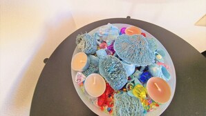 A round table with a variety of decorative items including candles, beads, and textured objects. - The Golden House (Siracusa)