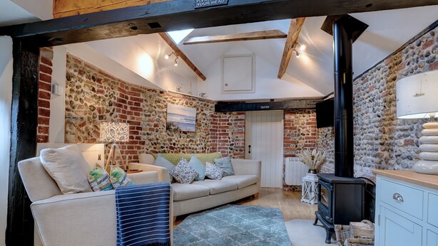 Una sala de estar acogedora con un sofá, una chimenea y una pared de piedra.
