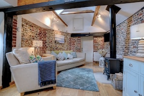 A cozy living room with a sofa, a fireplace, and a stone wall.