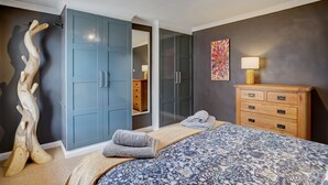 Una camera da letto con un letto grande, un armadio, una cassettiera in legno e uno specchio.