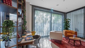A modern living room with a dining area, featuring a bookshelf, a coffee table, and a sofa. - Hotel iNova (Zagreb)