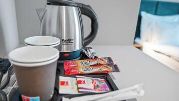 A coffee maker, a disposable cup, and packaged snacks on a hotel room table.