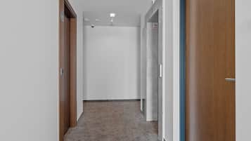 A hallway with a wooden door, a white wall, and a marble wall.