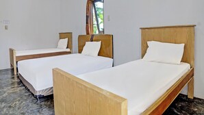 Ein Zimmer mit zwei Holzbetten, weißer Bettwäsche und einem Fenster mit Vorhängen.