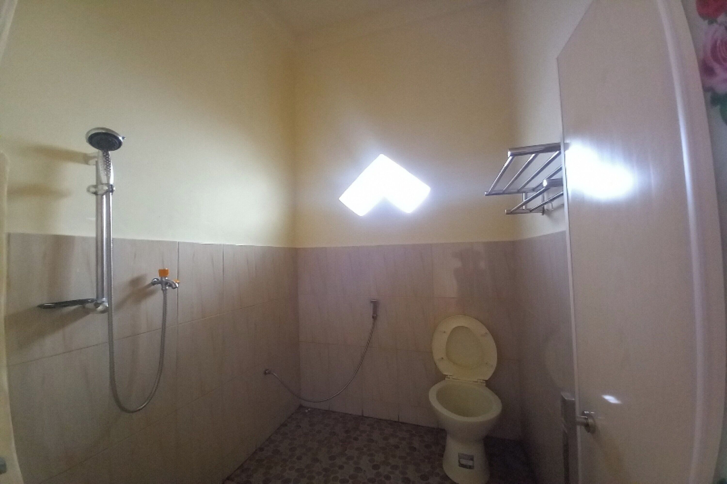 A small bathroom with a shower, toilet, and a light fixture on the wall.