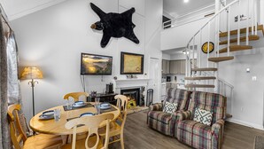 Een moderne woonkamer met een open haard, een eethoek en een trap.