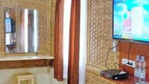 Ein Zimmer mit einem Holztisch, einem Fernseher und einem Fenster mit Vorhängen.