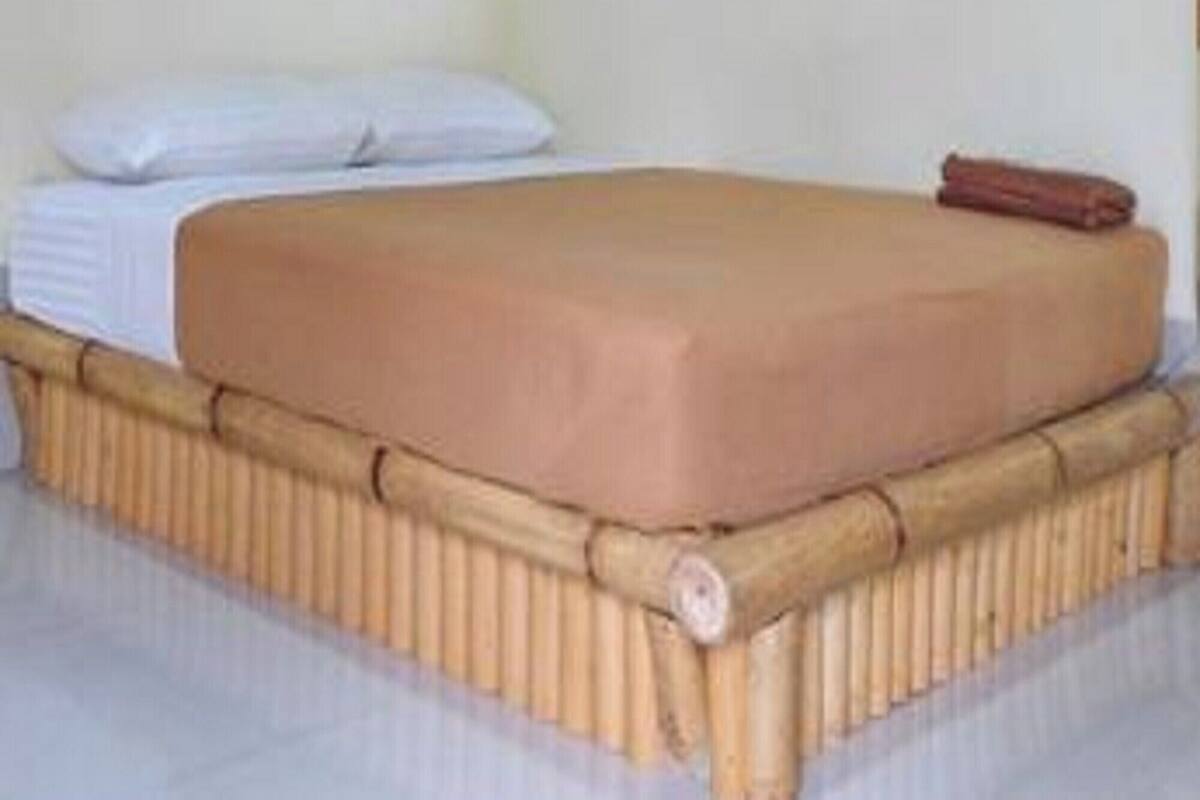 Ein Einzelbett mit Holzrahmen, einer Matratze, einem Kopfkissen und einer Decke.