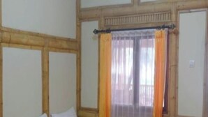Ein Zimmer mit zwei Betten, Holz-Kopfteilen, einem Vorhangfenster und Holzboden.