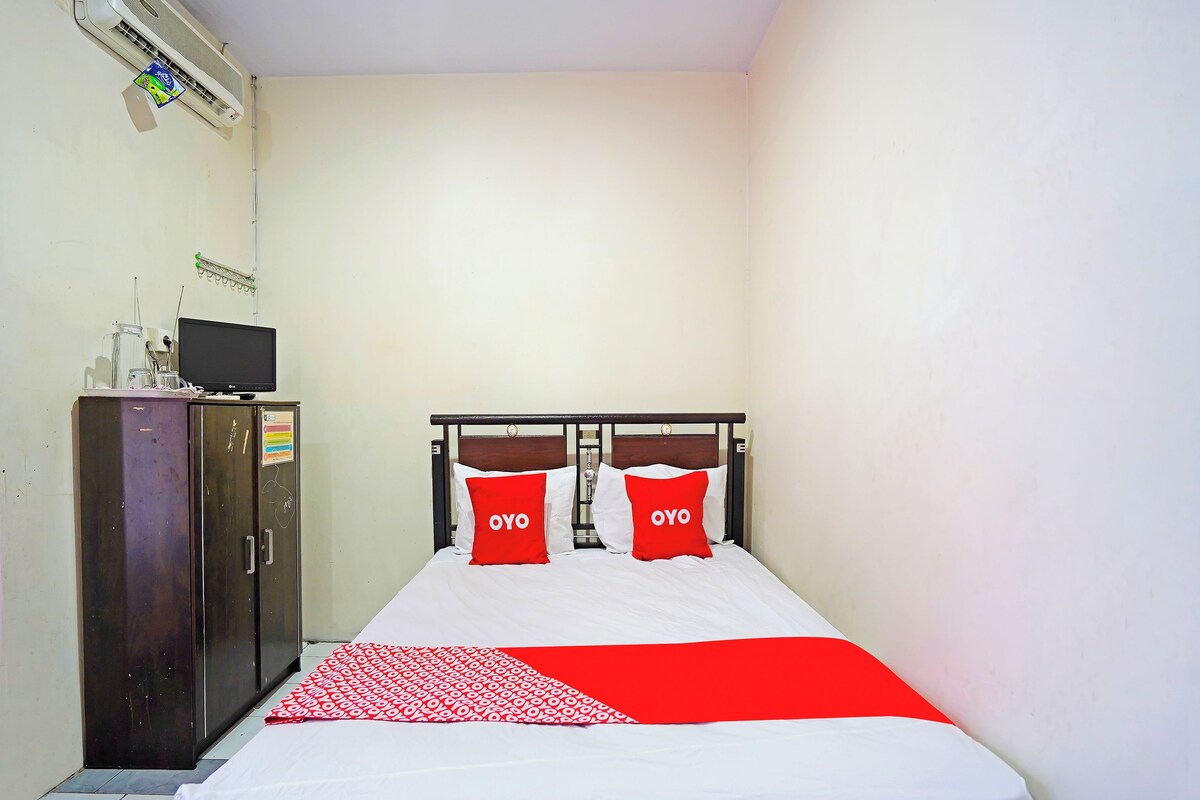 A bedroom with a bed, a wardrobe, and a television on a cabinet.