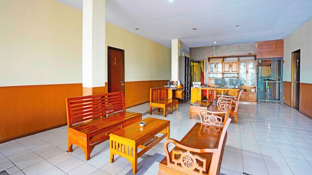 A spacious lobby with wooden furniture, a reception desk, and a kitchen area in the background. - OYO 91415 De Wijaya Hotel (Sidoarjo)