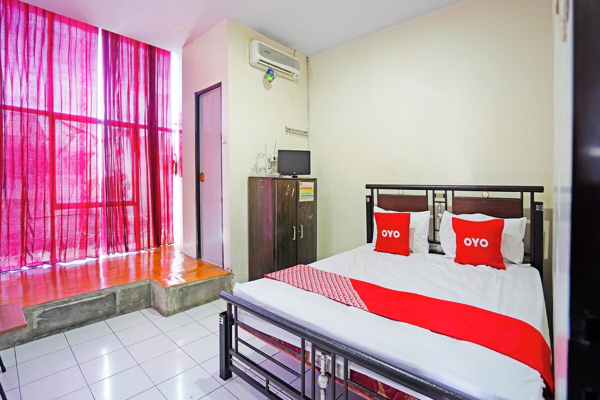 A hotel room with a bed, a wardrobe, a desk, and a window with curtains.