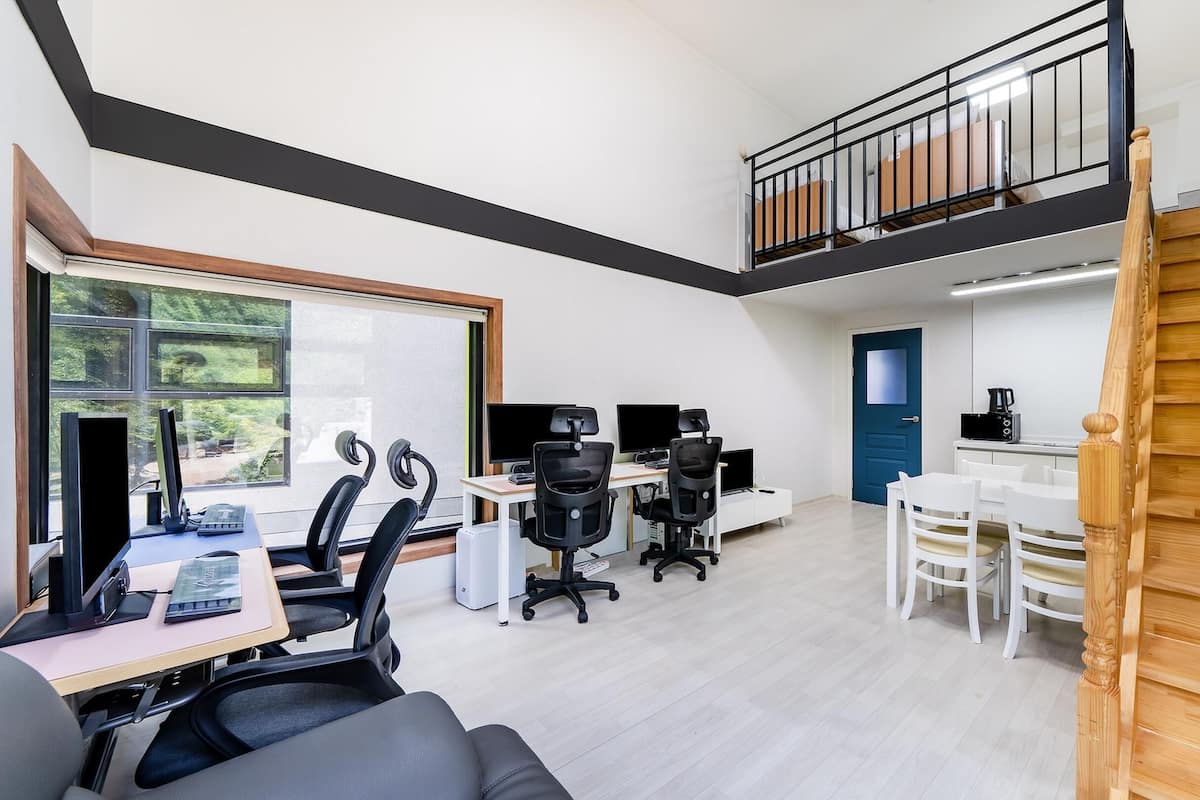 A modern office space with desks, chairs, computers, and a staircase.