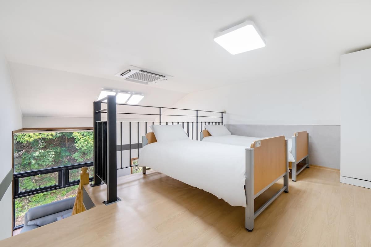 A modern bedroom with two beds, a balcony, and a large wardrobe.